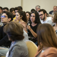 Una persona del público formula una pregunta a los ponentes